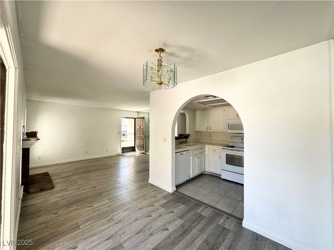 Kitchen featuring open floor plan, dark wood-type flooring, white appliances, and white cabinets | Image 6