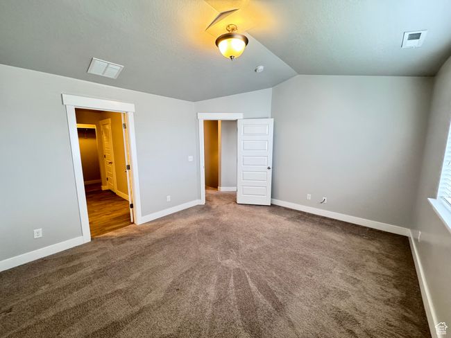 Unfurnished bedroom featuring baseboards, visible vents, lofted ceiling, and carpet flooring | Image 13