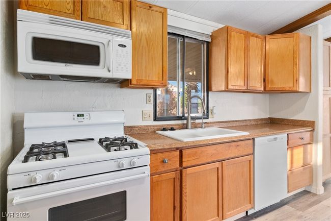 Kitchen with light countertops, white appliances, a sink, and light wood-style flooring | Image 12
