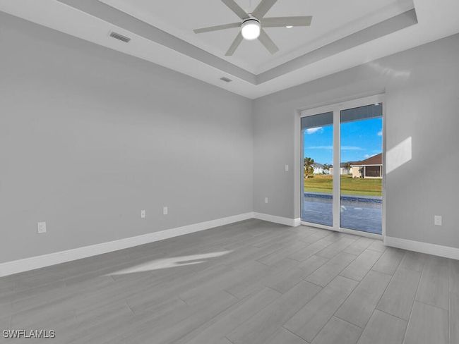 Empty room featuring a tray ceiling, ceiling fan, and wood finished floors | Image 18