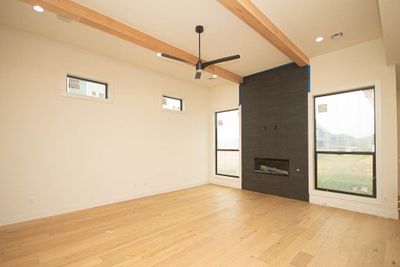 The living room boasts a sleek gas linear fireplace, adding warmth and a touch of modern elegance, while custom beams overhead provide architectural interest. | Image 3