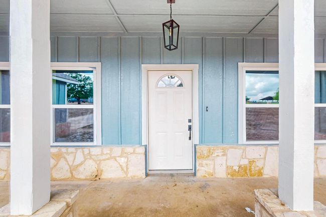 View of exterior entry with board and batten siding and stone siding | Image 9