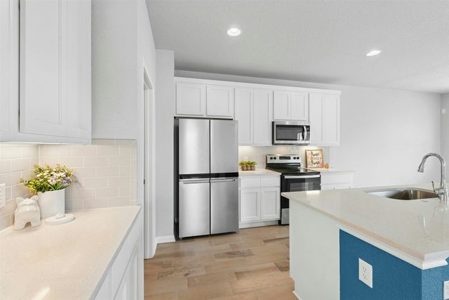 Kitchen featuring stainless steel appliances, backsplash, light wood-style floors, white cabinets, and recessed lighting | Image 16