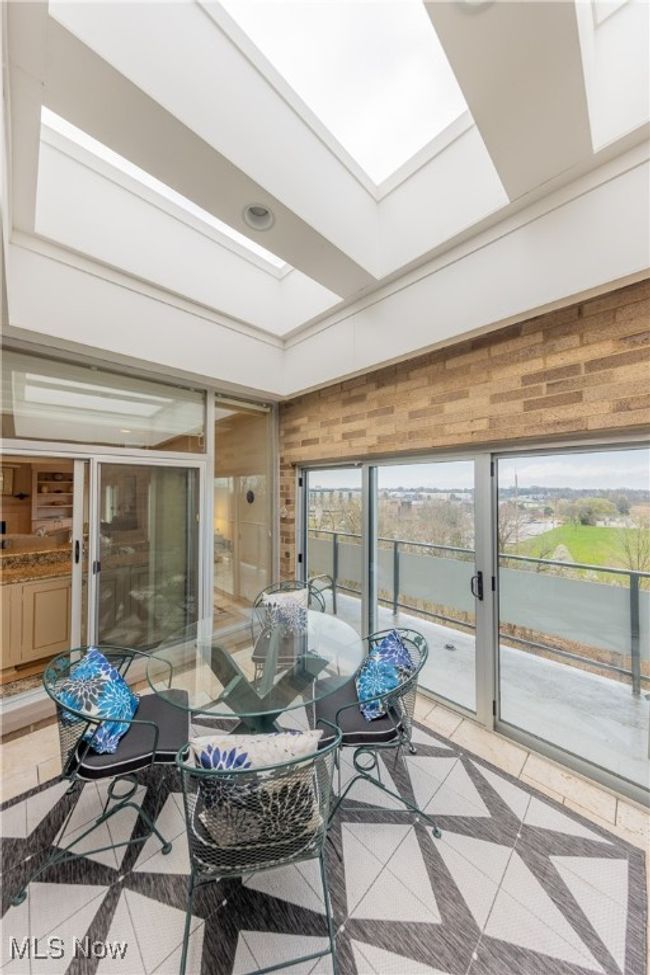Sunroom featuring tile flooring, a skylight, outdoor dining area, sliders to balcony | Image 21