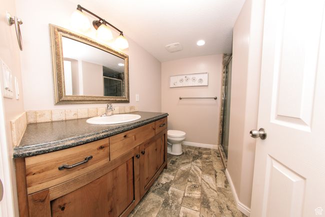 Downstairs Bathroom featuring a toilet, an enclosed shower, a vanity, and a tile floor. | Image 31