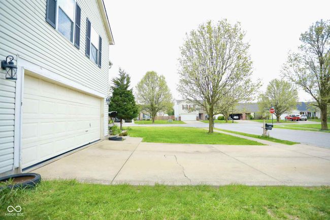 view of yard featuring driveway, a residential view, and an attached garage | Image 4