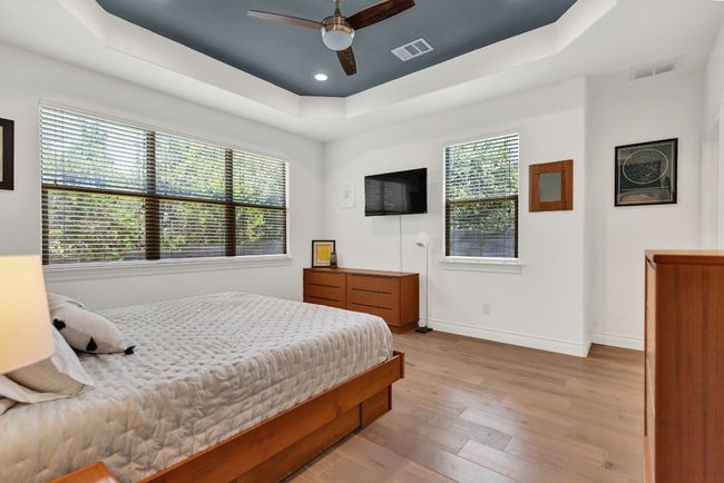Bedroom featuring wood finished floors, a tray ceiling, a ceiling fan, and recessed lighting | Image 12