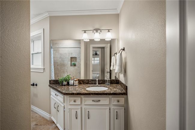 Full bath with baseboards, a textured wall, a tile shower, crown molding, and vanity | Image 30