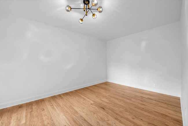 Unfurnished room with a chandelier and wood finished floors | Image 12