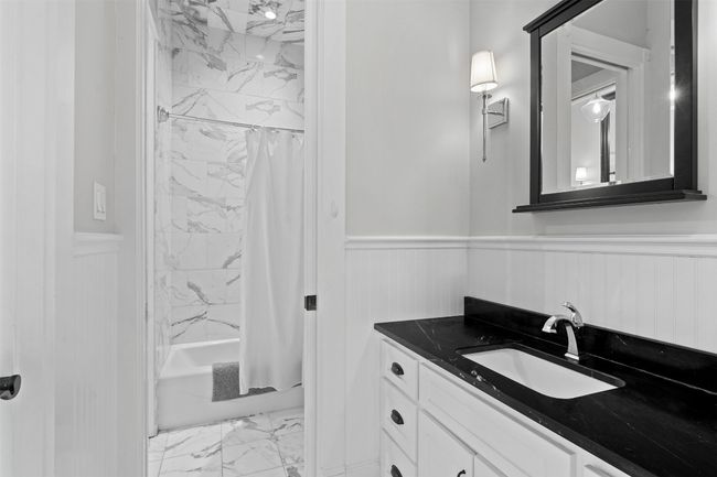 Full bathroom featuring shower / tub combo with curtain, vanity, marble finish floor, and a wainscoted wall | Image 22