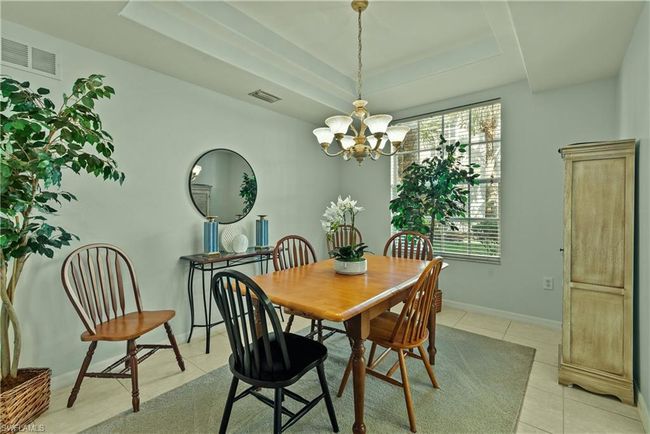 Dining space with a tray ceiling, light tile patterned floors, and a chandelier | Image 5