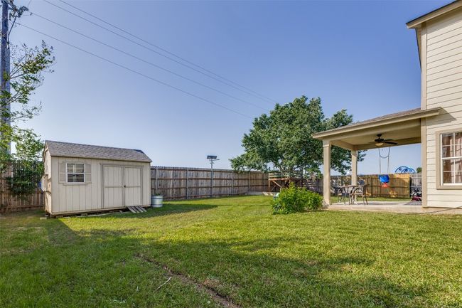 View of yard featuring a ceiling fan, a patio area, a storage shed, and an outbuilding | Image 37