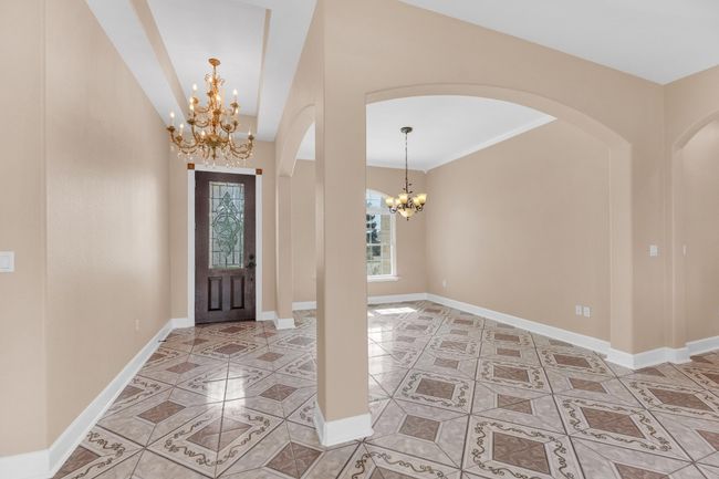 Tiled entryway featuring a chandelier, arched walkways, and ornamental molding | Image 7