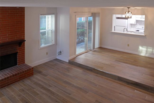 Unfurnished living room featuring a brick fireplace, a chandelier, and Luxury Vinyl Plank flooring | Image 10