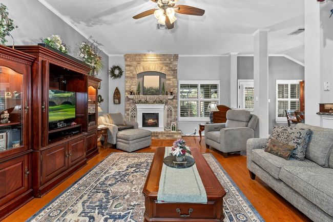 Living room featuring light hardwood / wood-style flooring, ornamental molding, a large fireplace, and ceiling fan | Image 5