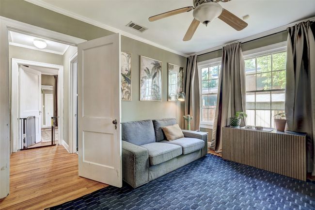 Living area with radiator heating unit, wood finished floors, visible vents, and crown molding | Image 19