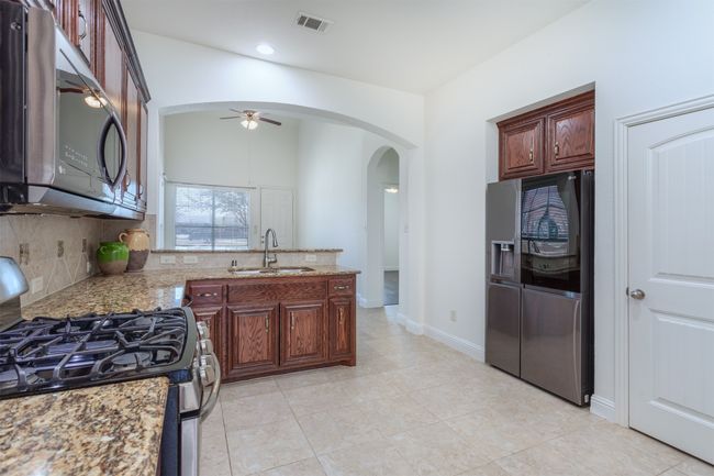 Kitchen with a ceiling fan, visible vents, arched walkways, a sink, and appliances with stainless steel finishes | Image 13