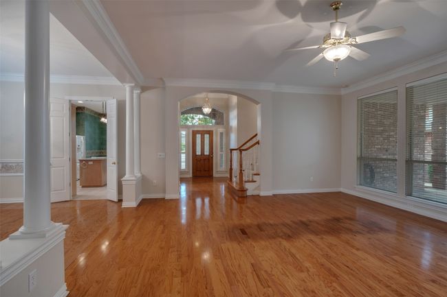 Foyer entrance with ornamental molding, light wood-style floors, baseboards, stairs, and decorative columns | Image 6