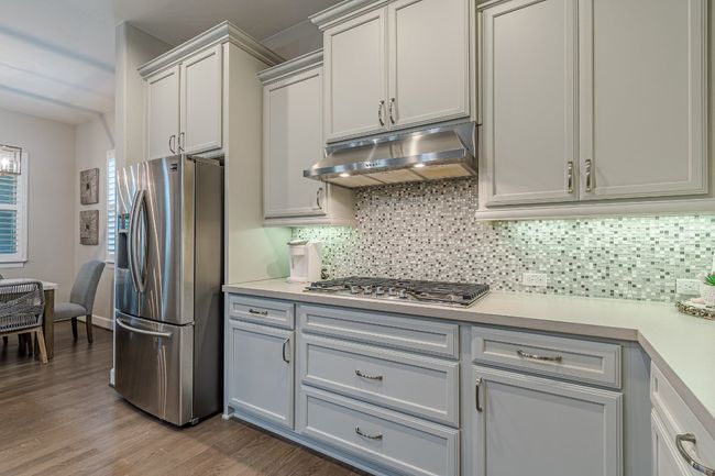 Kitchen featuring stainless steel appliances, under cabinet range hood, light countertops, and decorative backsplash | Image 16