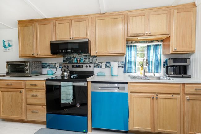 Kitchen with dishwashing machine, electric stove, and light brown cabinets | Image 16