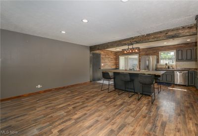 Kitchen with a textured ceiling, dark wood-type flooring, a kitchen island, beamed ceiling, and appliances with stainless steel finishes | Image 3