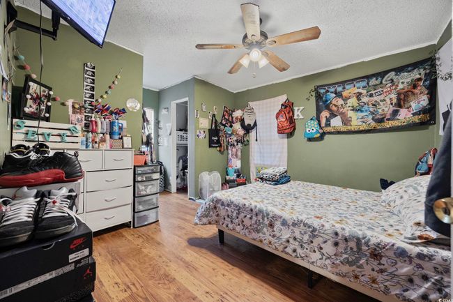 Bedroom with light wood finished floors, a textured ceiling, and ceiling fan | Image 7