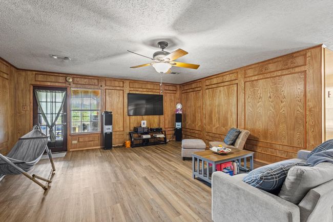 Living area with light wood-style flooring, ceiling fan, a textured ceiling, and wood walls | Image 14