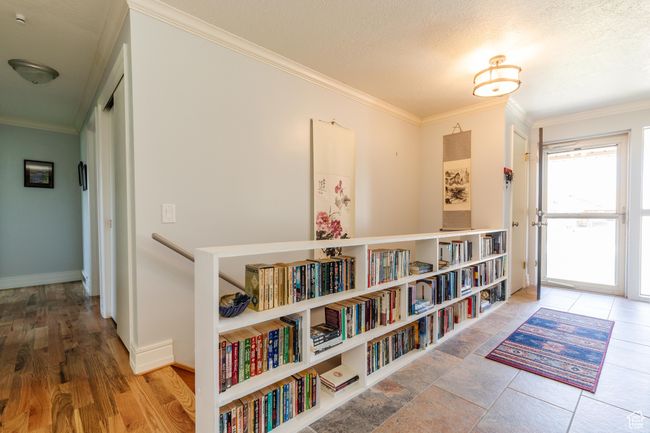 Hallway with a textured ceiling, crown molding, and baseboards | Image 12