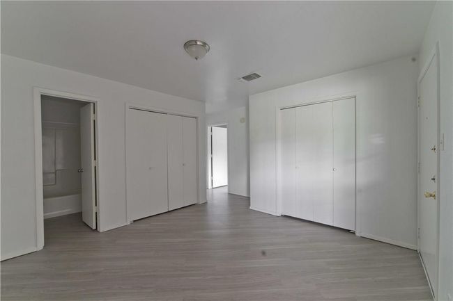 Unfurnished bedroom featuring wood finished floors, multiple closets, and ensuite bathroom | Image 6