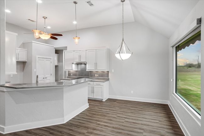 Kitchen with a wealth of natural light, white cabinets, dark wood-type flooring, and lofted ceiling | Image 32