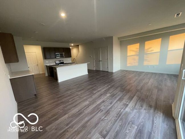 unfurnished living room featuring a sink, visible vents, baseboards, and dark wood finished floors | Image 8
