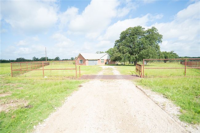 View of dirt / gravel road featuring a view of countryside and a gated entry | Image 13