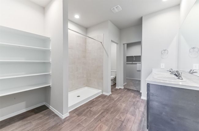 Primary bathroom with double sink, storage shelves, and large walk in shower. | Image 19
