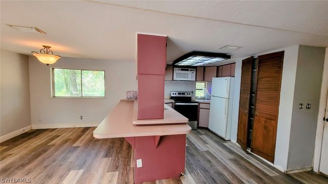 Kitchen featuring light hardwood / wood-style floors, white appliances, and a breakfast bar | Image 10