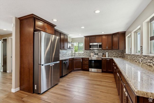 Kitchen with appliances with stainless steel finishes, granite countertops, wood LVP floors, recessed lighting, windows and backsplash | Image 7