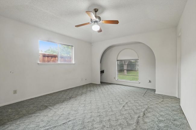Empty room featuring carpet flooring, a ceiling fan, arched walkways, and a textured ceiling | Image 24