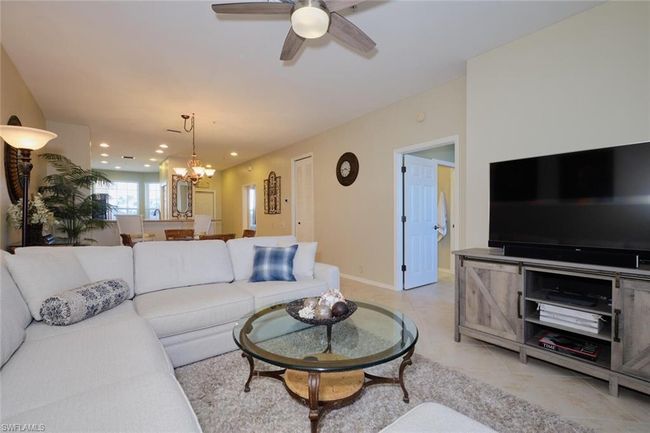 Tiled living room featuring ceiling fan with notable chandelier | Image 30