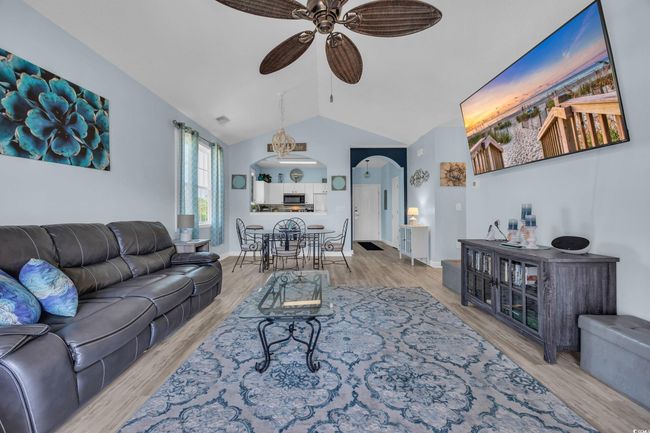 Living area with a ceiling fan, wood finished floors, arched walkways, and vaulted ceiling | Image 16