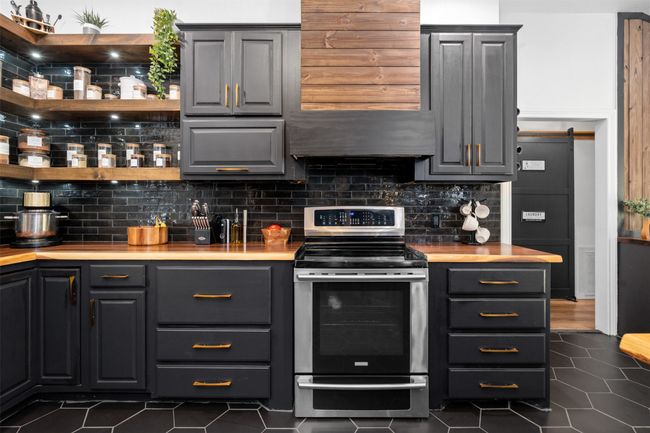 Kitchen featuring stainless steel electric range, gray cabinetry, tasteful backsplash, dark tile patterned flooring, and a barn door | Image 29