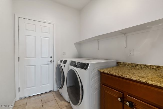Laundry room featuring washing machine and dryer, laundry area, and light tile patterned floors | Image 35