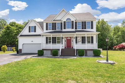 Colonial-style house with a garage, a front lawn, and covered porch | Image 2