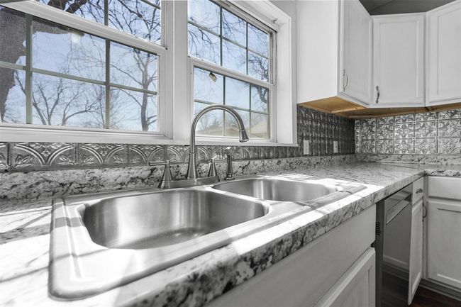 Kitchen with white cabinets, dishwasher, light countertops, and backsplash | Image 5