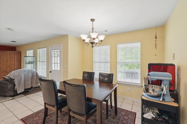 Dining space with a chandelier, light tile patterned floors, baseboards, and visible vents | Image 15