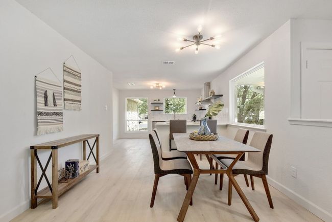 The dining room is flanked by the kitchen and living room, open to both, yet separated by a half wall. | Image 4