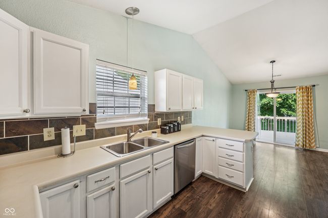 kitchen featuring dishwasher, a peninsula, dark wood-style floors, white cabinets, and backsplash | Image 14