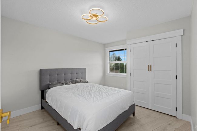 Bedroom with a closet, light wood finished floors, baseboards, and a textured ceiling | Image 27