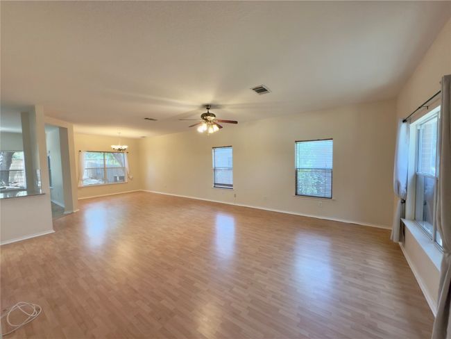 Unfurnished living room with a chandelier, light wood finished floors, and a ceiling fan | Image 14
