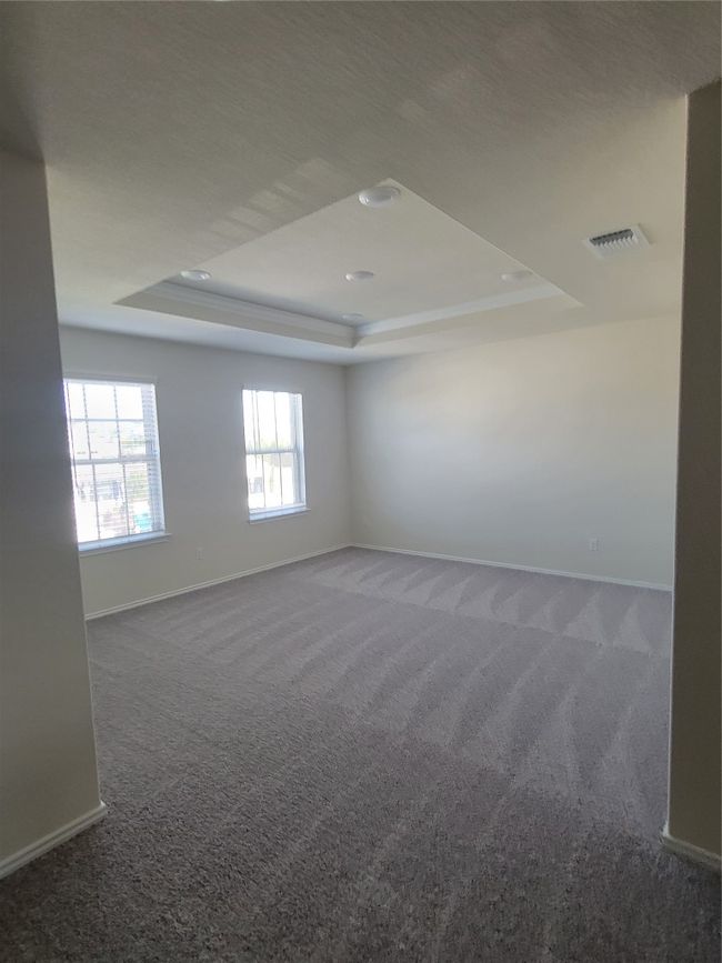 Carpeted empty room featuring a tray ceiling, baseboards, and visible vents | Image 17