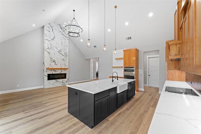 Kitchen featuring visible vents, dark cabinets, a sink, high vaulted ceiling, and an inviting chandelier | Image 12