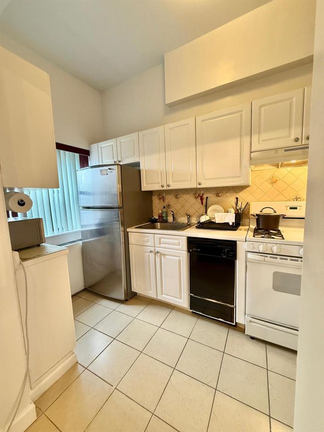 Kitchen featuring freestanding refrigerator, under cabinet range hood, white gas range, dishwasher, and a sink | Image 9